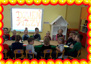 Dzieci siedzą przy stole. W tle napis Dzień Pizzy.